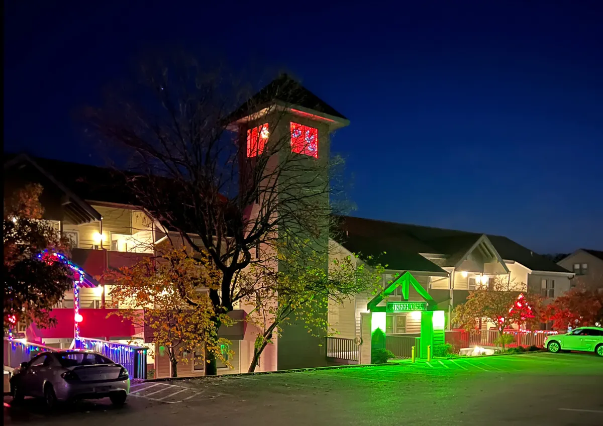 A brightly illuminated clock tower and festive entrance area adorned with colorful holiday lights. The scene captures an evening ambiance, suggesting lively group outings and memorable experiences in the Hwy 76 Entertainment District.