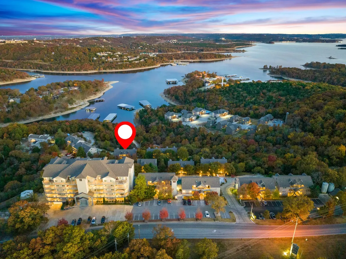 This scenic view showcases Table Rock Lake framed by lush forest with residential buildings in the background. The image conveys access to waterfront activities, boating, and peaceful natural surroundings—an ideal backdrop for family gatherings on the private deck after a thrilling day out.
