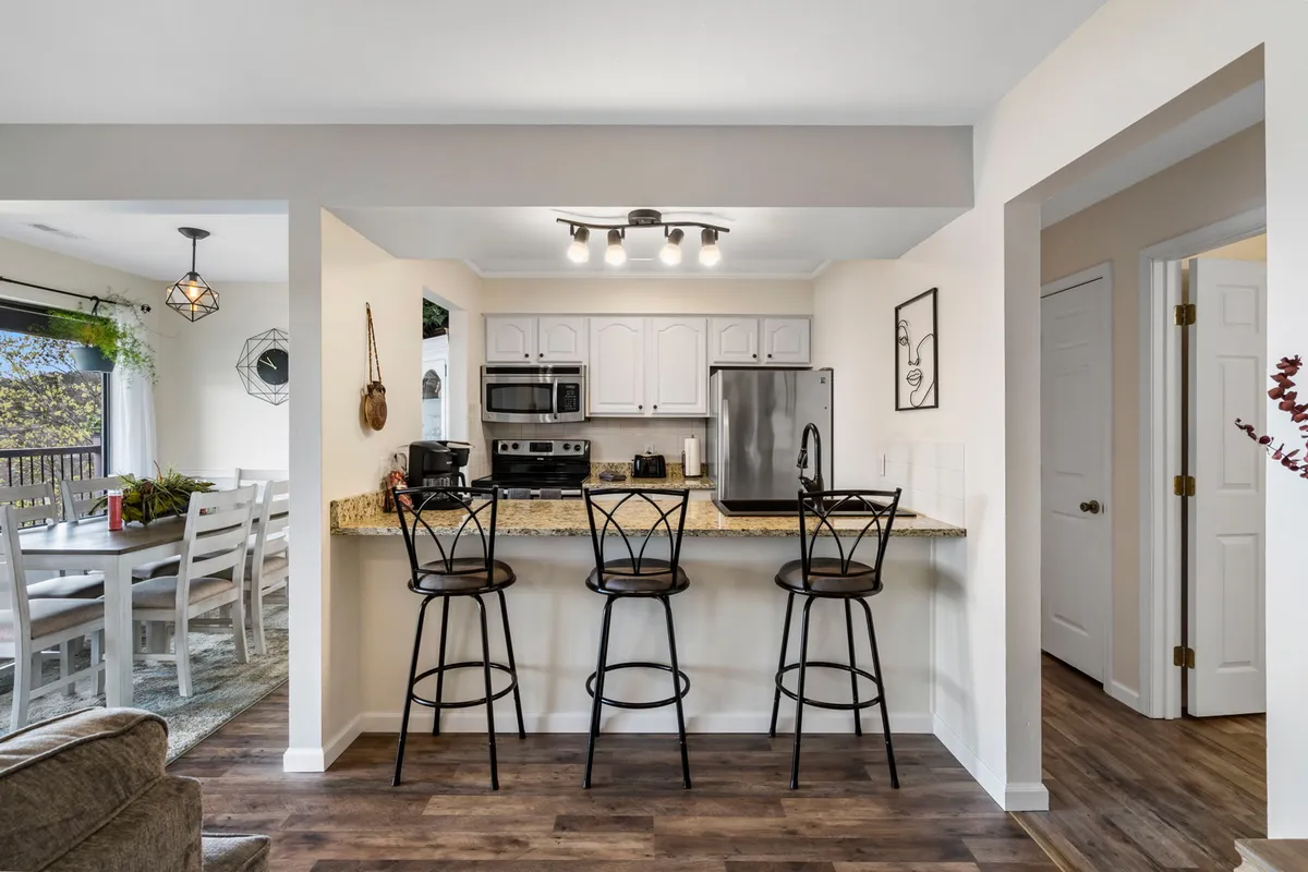 A welcoming interior shows an open-concept kitchen with a large island, bar stools, modern appliances, and a clear view of the adjacent dining area. This layout emphasizes the kitchen's role as the heart of group gatherings, supporting both cooking and social activities.