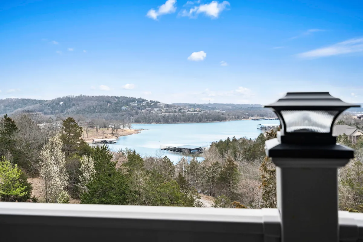 A tranquil, wide-angle view of Table Rock Lake with distant hills on the horizon and a dock extending into the water. The water is calm, and the light suggests either early morning or sunset, creating a romantic and serene ambiance ideal for couples seeking a peaceful retreat.