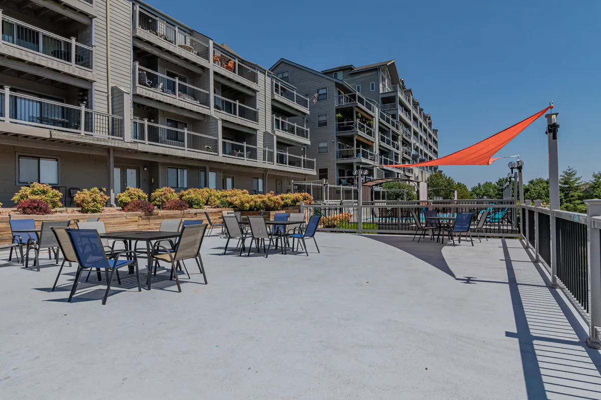 An inviting outdoor seating area with colorful planters and ample space for relaxation, set against the backdrop of the condo's facade. The seating area is designed for social gatherings or intimate conversations and features a direct view of the sunset.