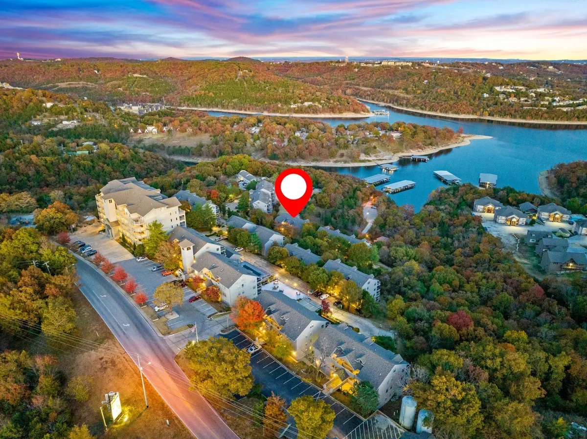 An expansive view of Table Rock Lake with autumn foliage framing the water, nearby buildings, and a peaceful road winding through the landscape. The open sky and serene atmosphere evoke the natural beauty and recreational opportunities of the area.